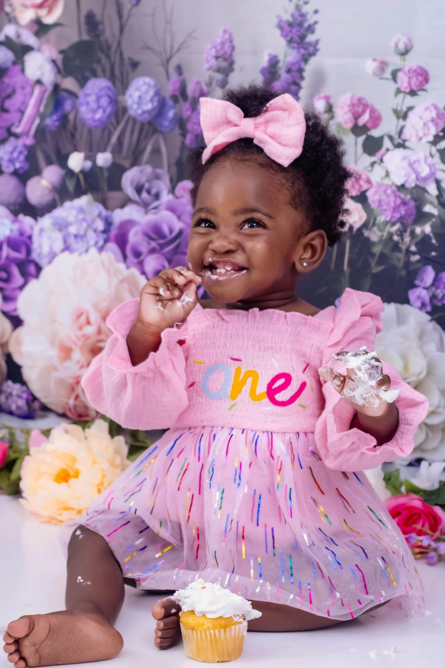 One-year-old smiling during a pink birthday portrait session